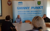 Urzednicy i mieszkany na tle napisu Gminny Punkt Konlultacyjno-informacyjny Programu Czyste Powietrze
