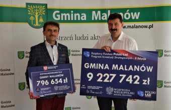 Wojt Malanowa oraz sekretarz stanu Ryszard Bartosik trzymaja tablice informacyjna dotyczaca dofiansowan