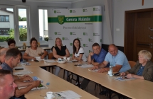 grupa osób siedząca przy stle w tle ścianka reklamowa