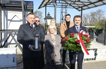 grupa stojących osób. Jeden trzyma wiązankę kwiatów