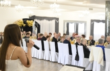 śpiewająca kobieta w tle siedzący przy stole goście