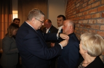 Mezczyzna w ciemnym garniturze przypina odznaczenie