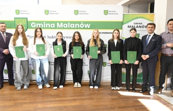 Grupa osób trzyma zielone teczki