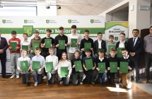 grupa osób z zielonymi teczkami pozuje do zdjęcia