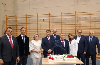 grupa stojacych osob. Przed osobami tort