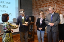 Kobieta i mezczyzna podaja sobie rece. Obok dwie osoby