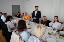 grupa siedzacych osob i stojacy mezczyzna