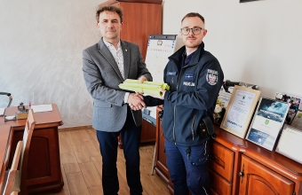 dwóch mężczyzn w tym policjant podaje sobie dłonie i trzymaja odblaski