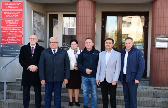 grupa osob stojaca przed budynkiem urzedu gminy